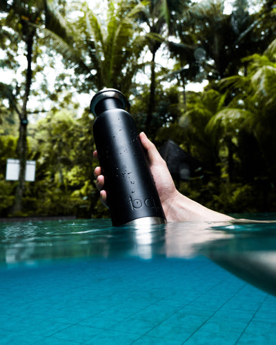 Drinking with black water bottle in summer pool